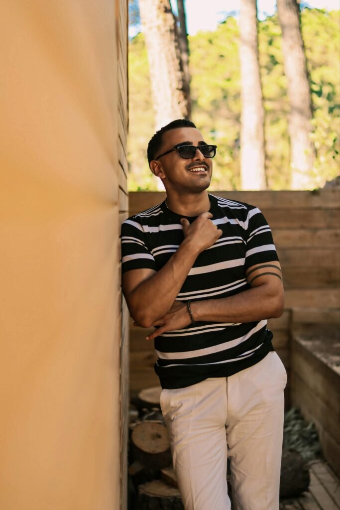 Man styling a black striped knit t-shirt with white trousers for a clean summer casual outfit